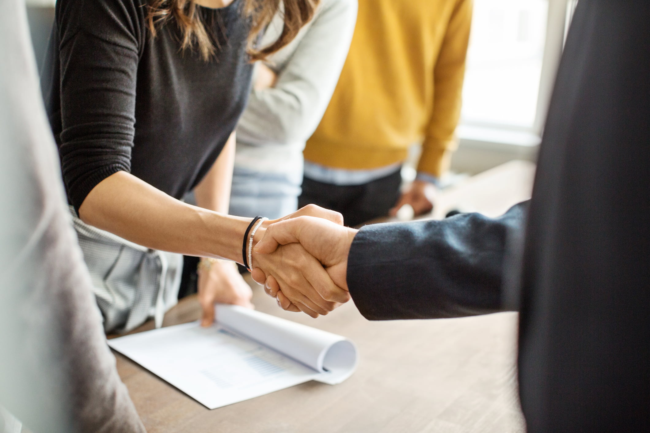 Business people shaking hands in office Two people shaking hands over a table with documents in a California office, signifying professional collaboration and agreement, possibly related to bail bonds or jail bond discussions.