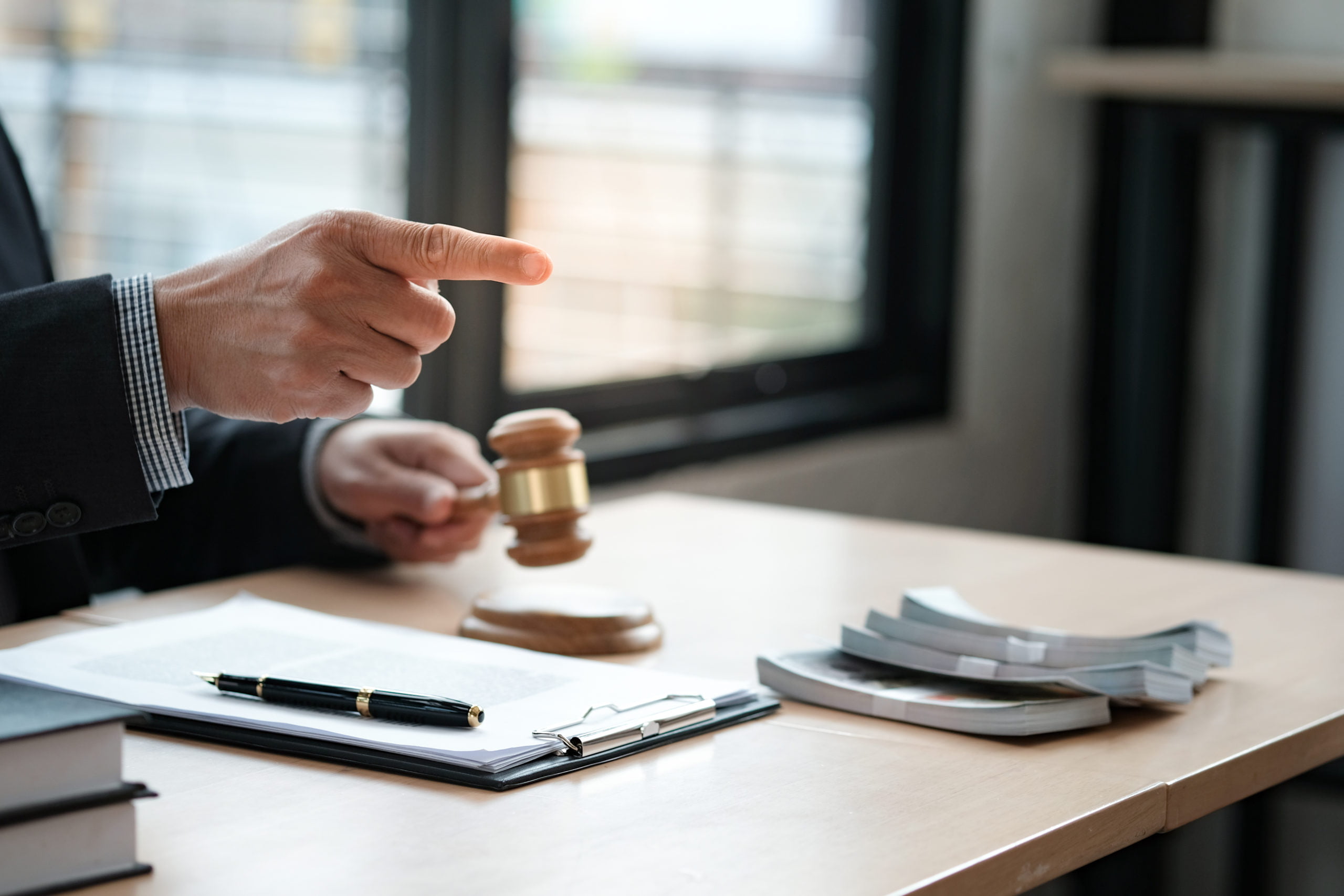 Lawyer Auction bid sale judgment mallet with judge. Auctioneer k In an office setting, a person in a suit points with authority while holding a gavel, surrounded by documents and a pen on the desk—setting the scene for discussions about bail procedures in California.
