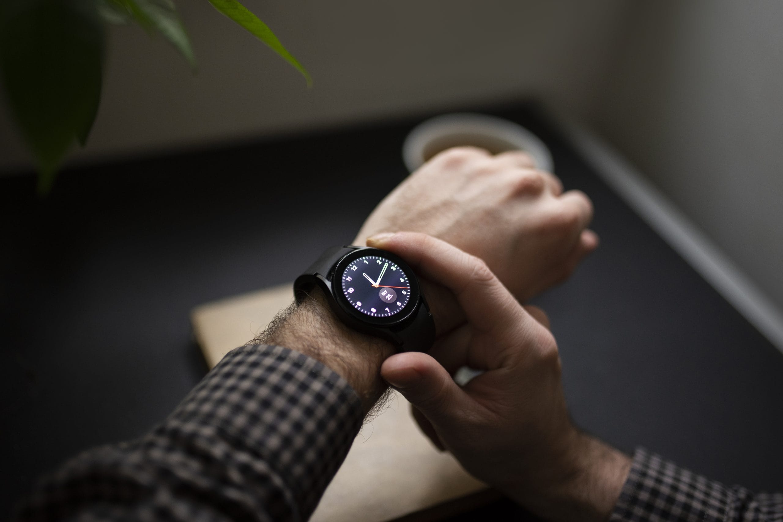 Mateo Gobo photography Person wearing a smartwatch and checking the time, with a coffee cup and book in the background.